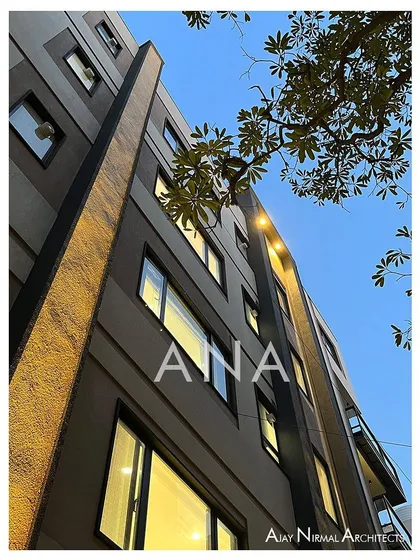 A low-angle shot of the Yellow Line Apartment facade at twilight. Up-lighting accentuates the vertical lines, giving the building a dramatic presence in the evening.