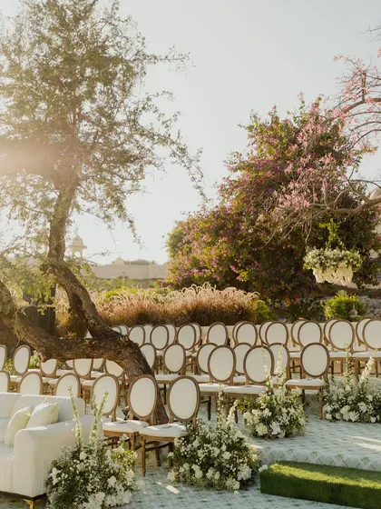 An elegant ceremony seating arrangement under the trees, with white florals lining the aisle. We design the guest seating to be comfortable while offering a beautiful view of the proceedings.