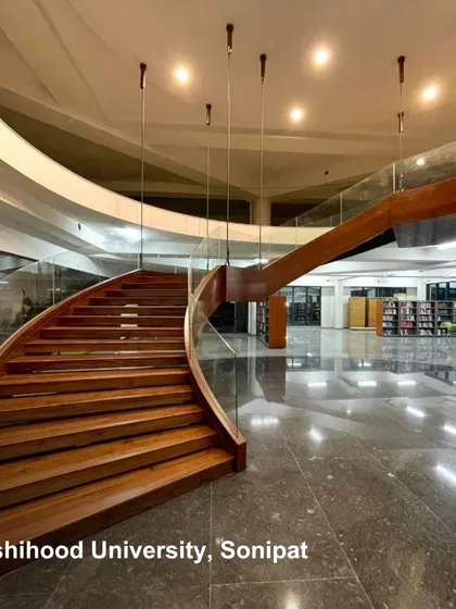 The grand, curving staircase at Rishihood University, Sonipat, serves as a central architectural feature. It connects floors within a large, open-plan space, encouraging movement and visual connection across different levels of the institution.