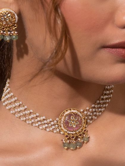 A close-up of our rice pearl moti choker. This piece enhances your elegance with its fusion touch of a central carved stone, Kundan work, and delicate green bead droplets.