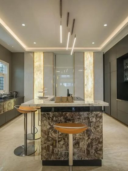 A luxurious kitchen designed for a culinary enthusiast, featuring dark cabinetry, a textured stone island, and dramatic pendant lighting. The large window allows for plenty of natural light, creating a perfect workspace.