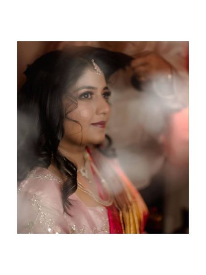 A candid shot of the bride getting her hair styled, captured with a soft, dreamy effect. It's a quiet, behind-the-scenes moment.