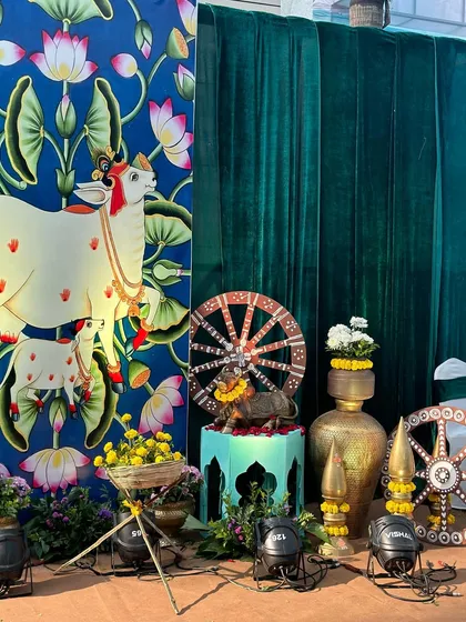 A beautiful corner from our Vrindavan theme, featuring a Pichwai-style painting of a cow and calf, along with traditional brass pots and other decor elements.