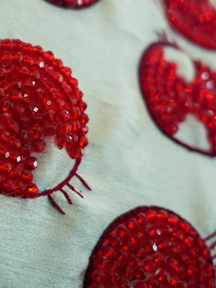 A close-up of the hand-beaded cushion covers, featuring pomegranate designs made with red beads and crystals by village club girls.