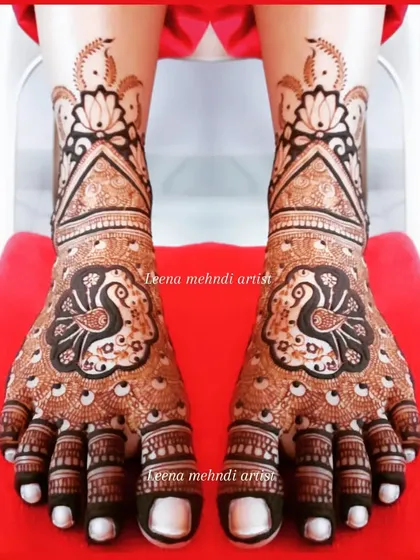 A classic bridal foot design featuring a central peacock on each foot. The feathers create a beautiful pattern over the toes, and the design extends up the ankle with lotus motifs.