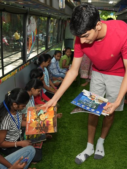 A volunteer distributes books to children inside our mobile classroom. Our initiative often collaborates with other organizations to bring literacy and arts together.