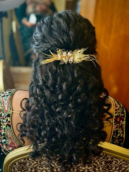 A closer look at the curly half-updo, showing how the gold accessory complements the hair's natural texture.