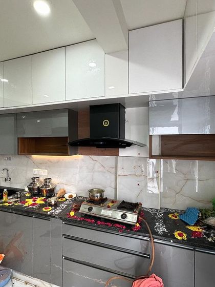 A kitchen space during a housewarming, showcasing the two-tone grey and white modular cabinets. Our factory-finished modules ensure a perfect fit and a flawless look upon installation.