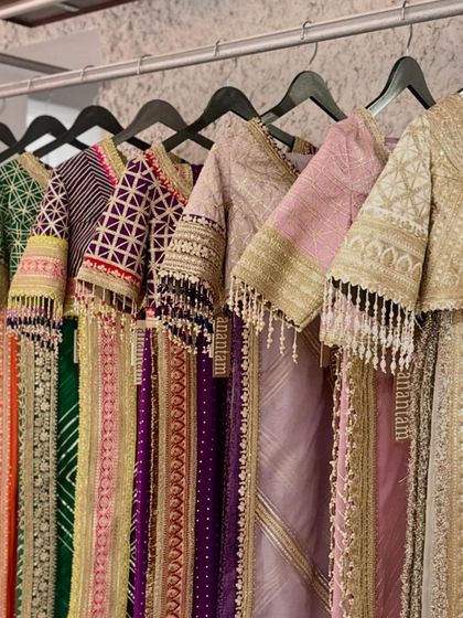 A rack of vibrant sarees by Shikhar Sharma, showcasing a rainbow of colors and intricately embroidered blouse sleeves with tassel details.