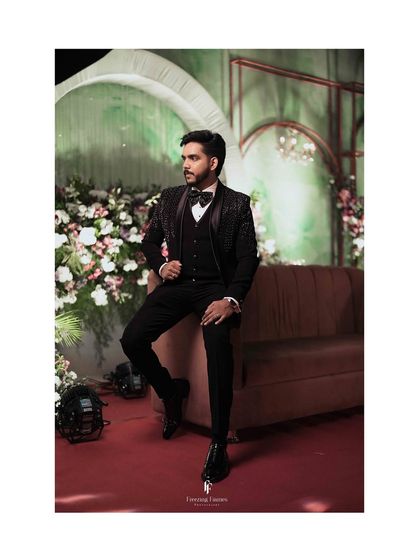 A solo shot of the groom seated on a sofa at his reception, looking confident and stylish.