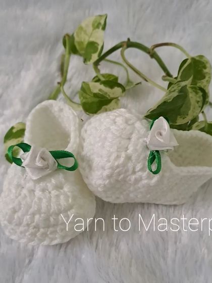 Simple yet elegant, these white booties are adorned with a single white satin rose and a green ribbon leaf, perfect for a garden-themed event.
