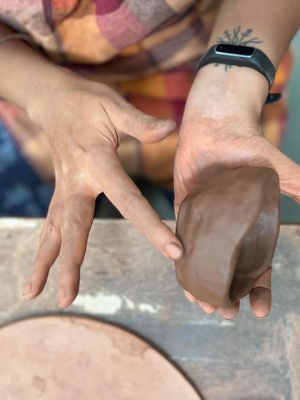 Before the work begins, there is the simple act of feeling the clay. This close-up shows a participant connecting with the material at the start of a corporate team building session.