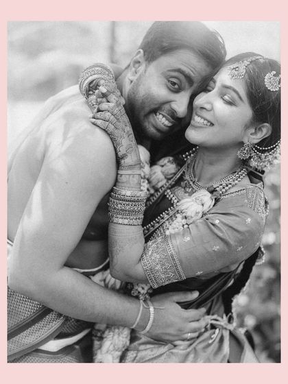 A warm, joyful embrace. This black and white portrait of Venkai and Sruthi, framed with a soft pink border, highlights their happiness and the beautiful intimacy of their wedding day.