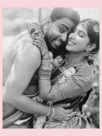 A warm, joyful embrace. This black and white portrait of Venkai and Sruthi, framed with a soft pink border, highlights their happiness and the beautiful intimacy of their wedding day.