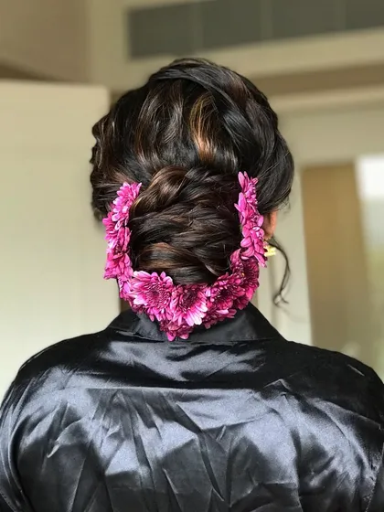 The final placement of the floral garland on the textured bun, creating a stunning and cohesive bridal look.