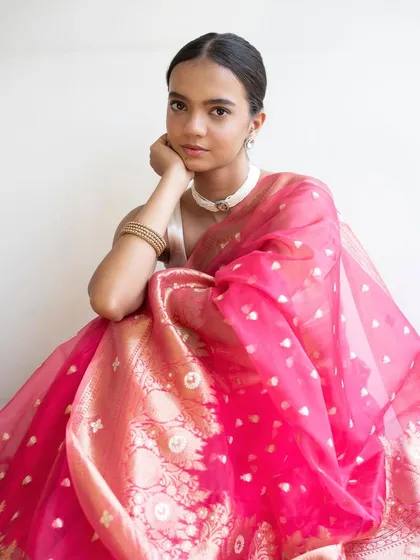 A simple and elegant portrait. The clean makeup and simple hairstyle allow the vibrant color of the saree and the model's natural beauty to be the focus.