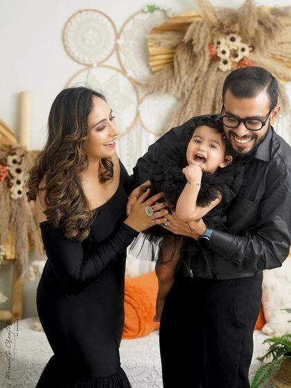 A candid moment of pure laughter. This family portrait in matching black outfits captures a genuine interaction that is full of joy and life.