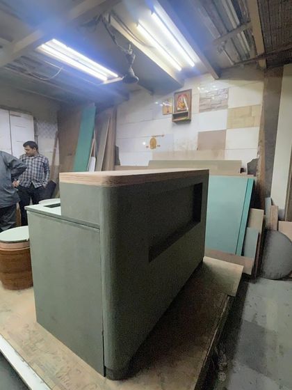 A behind-the-scenes look at the Entisi reception counter being fabricated in the workshop. This shows the solid construction and form before the final finishes of paint, brass, and wood were applied.