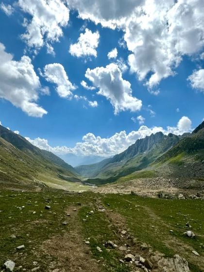 A moment of rest in a vast green valley under a brilliant blue sky. These are the moments of peace and connection that define our Himalayan adventures.