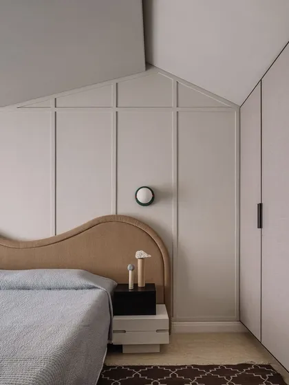 The guest bedroom's design incorporates clever storage solutions within the paneled walls, maintaining a clean and uncluttered aesthetic.