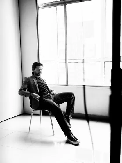 A relaxed and confident black and white portrait of an actor, shot with natural light in a studio. This has a classic, cinematic feel.