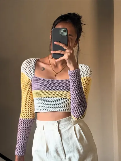 A mirror selfie showing off this color-blocked mesh sleeve top. The combination of yellow, purple, and white gives it such a fun, pastel vibe.
