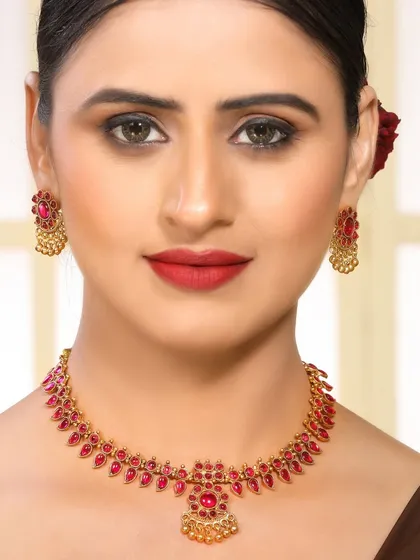 A direct, engaging shot of a model wearing a traditional gold and ruby necklace. The clear view of the design is perfect for product detail pages on e-commerce websites.