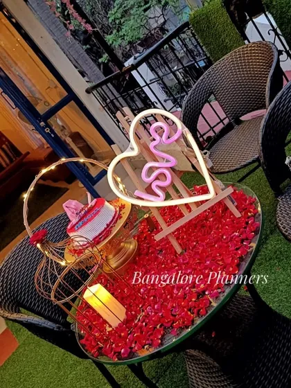 A simple and sweet table setup for two at a cafe. I used a bed of red rose petals, a neon 'Love' sign, and a candle to create an intimate space for an anniversary celebration.