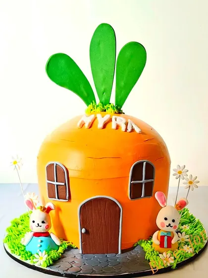 A unique carrot house cake for a bunny-themed party. This sculpted cake is shaped like a giant carrot, with two adorable bunnies outside, making it a standout centerpiece.