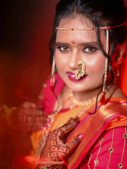 A close-up bridal portrait with a creative red flare effect, highlighting her expressive eyes and traditional 'mundavalya'.