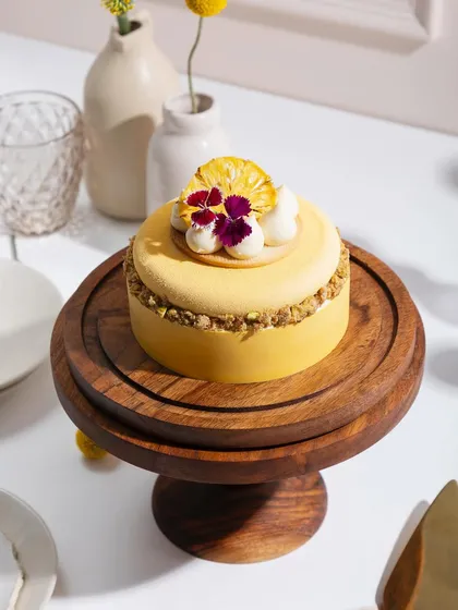 Our Lemon and Pineapple cake, presented on a wooden stand, brings a touch of tropical sunshine to your dessert table.