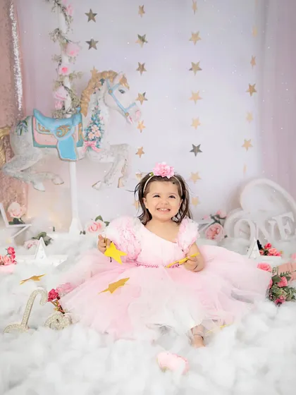 A magical first birthday. This little princess is all smiles in our dreamy carousel-themed setup, surrounded by clouds, stars, and flowers.