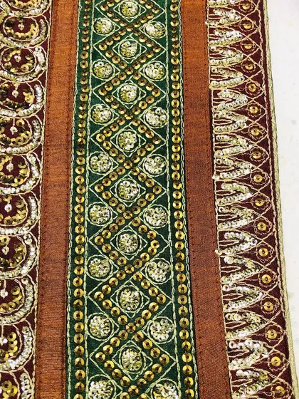 A rich and opulent saree border featuring intricate sequin and zari work in green, maroon, and gold. This heavy designer lace is ideal for bridal wear and special occasion outfits.