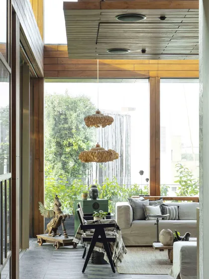 Looking into the conservatory from an adjacent space, this view captures the room's connection to the lush greenery outside. The wooden ceiling and window frames add warmth to the design.