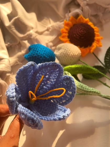 A simple, beautiful shot of individual crochet flower stems, including a sunflower and tulips. This photo highlights the "golden glow" of the flowers in the sunlight.