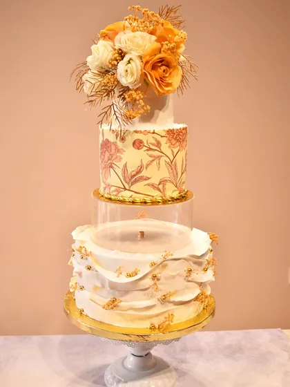 A stunning four-tier cake for a 40th anniversary, featuring a floating tier design. The cake combines hand-painted floral patterns, delicate ruffles with gold accents, and a beautiful bouquet of sugar flowers on top.