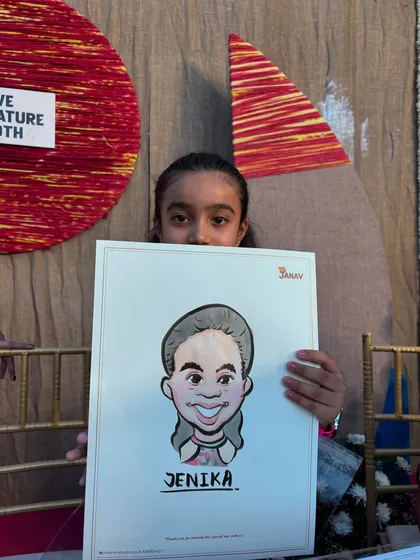 A young girl peeking over her freshly drawn caricature at a live event booth. These on-the-spot drawings are always a highlight for kids at parties.