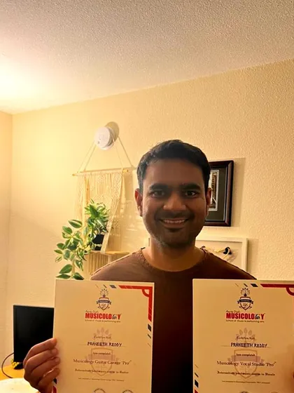 A happy student, Praveeth, proudly displays his certificates for completing the Guitar Garage Pro and Vocal Studio Pro courses.