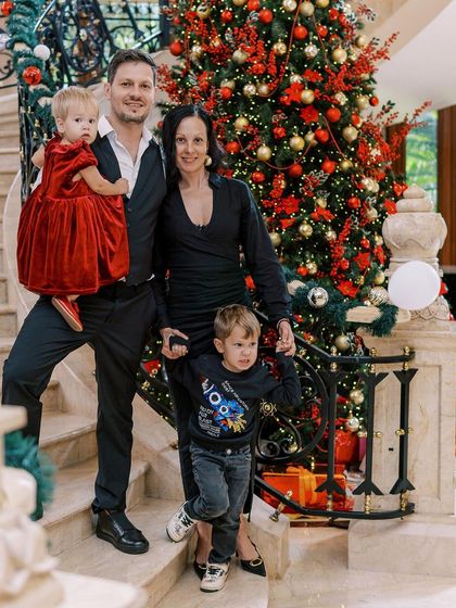 A formal family portrait on the stairs in front of a grand Christmas tree. A beautiful and elegant way to capture a holiday memory.