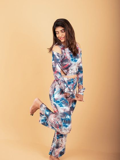 A fun and dynamic studio portrait. The playful pose and patterned outfit create a high-energy image that stands out.