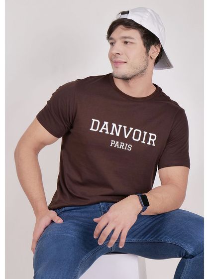 A model in a brown version of the same t-shirt, demonstrating how we maintain a consistent look for different product colorways.