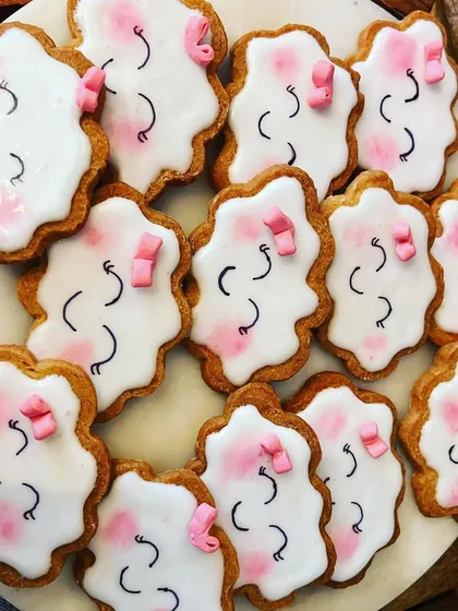 Adorable custom-decorated cookies for a baby shower, shaped like smiling clouds with little pink bows.