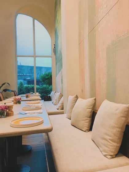 The serene and spacious interior of our cafe at The Dhan Mill. The high ceilings, large windows, and soft colors create a calming and beautiful dining environment.