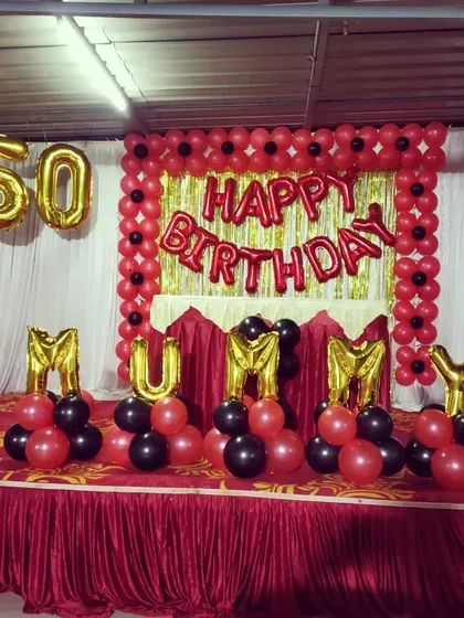 A close-up of the 50th birthday stage decoration with 'MUMMY' foil letters.