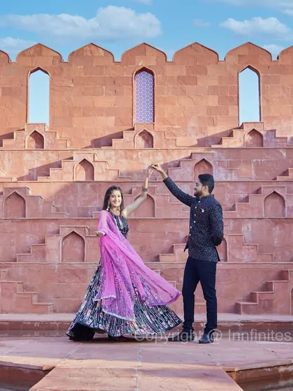 A dance frozen in time at our Rajasthani-style stepwell set. The unique architecture and the couple's elegant pose create a visually striking pre-wedding photograph.