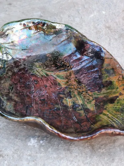 This is the unpredictable beauty of Raku. The intense heat and smoke create these incredible, iridescent colors and crackle patterns. This leaf-shaped dish looks like a piece of captured galaxy.