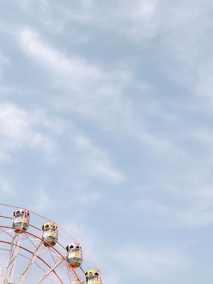 A cropped view of the Ferris wheel, focusing on the colorful cabins against the sky. This is a simple, clean shot that highlights the cheerful colors of the carnival.