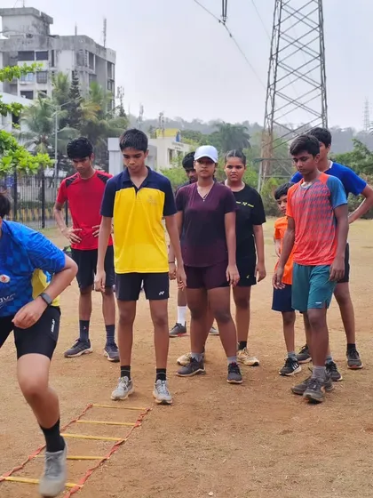 An outdoor training session where players work on their footwork and speed using an agility ladder on an uneven surface to improve stability.