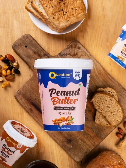 A top-down flat lay of Quantum Nutrition's peanut butter, surrounded by its ingredients like nuts and bread. This styling connects the product to a healthy, wholesome lifestyle.