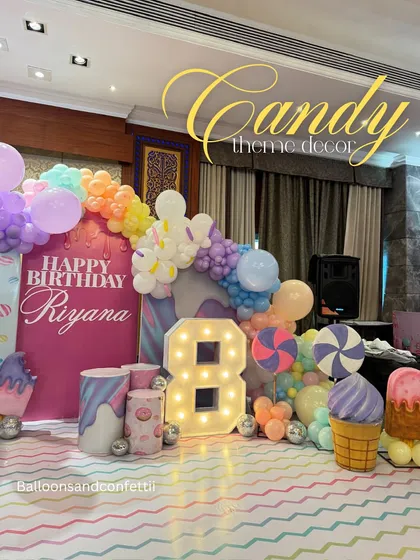 A closer look at the Candyland decor, with giant ice cream cone props and a pastel rainbow balloon garland.